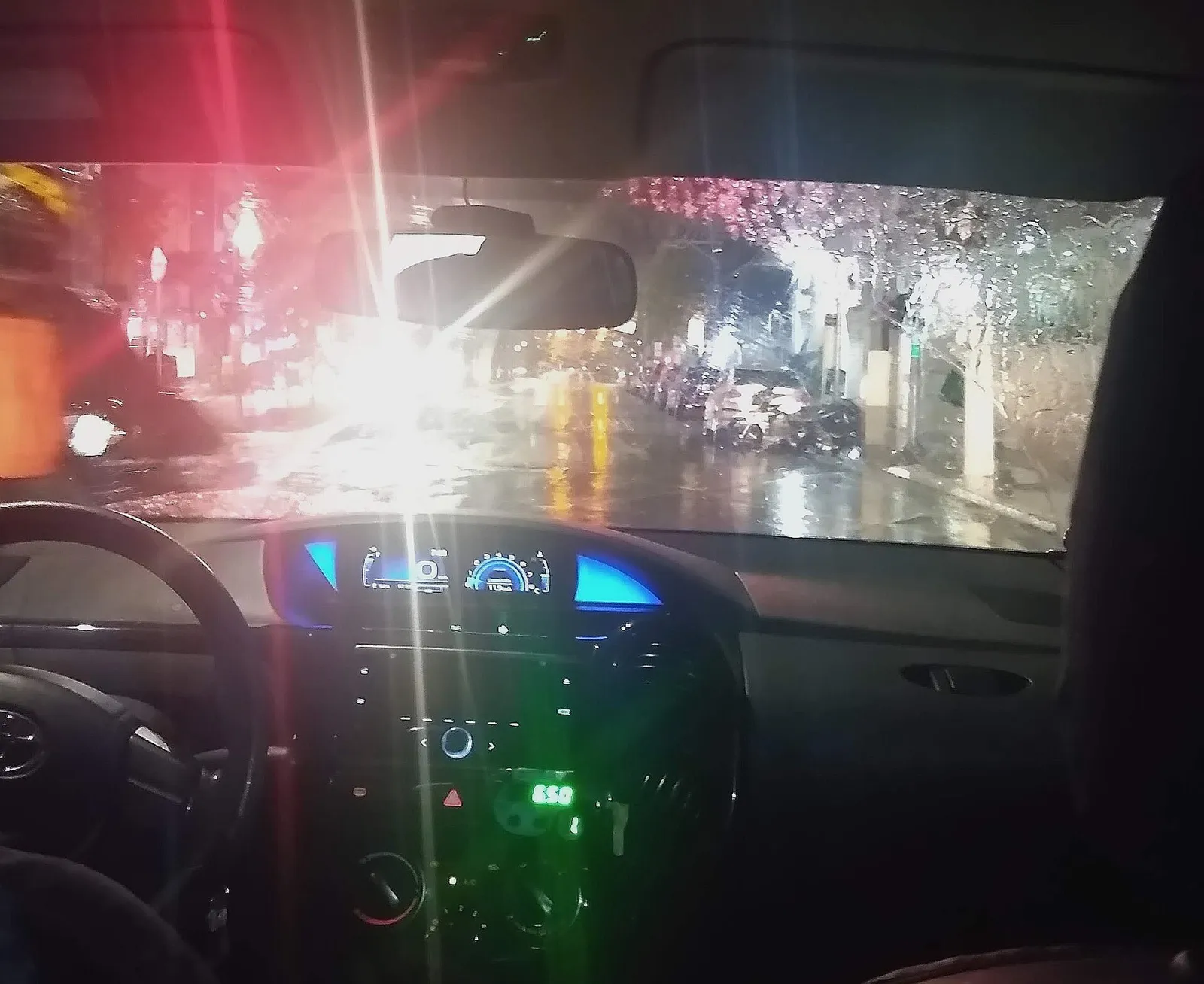 Painel de táxi visto de dentro, em noite de chuva